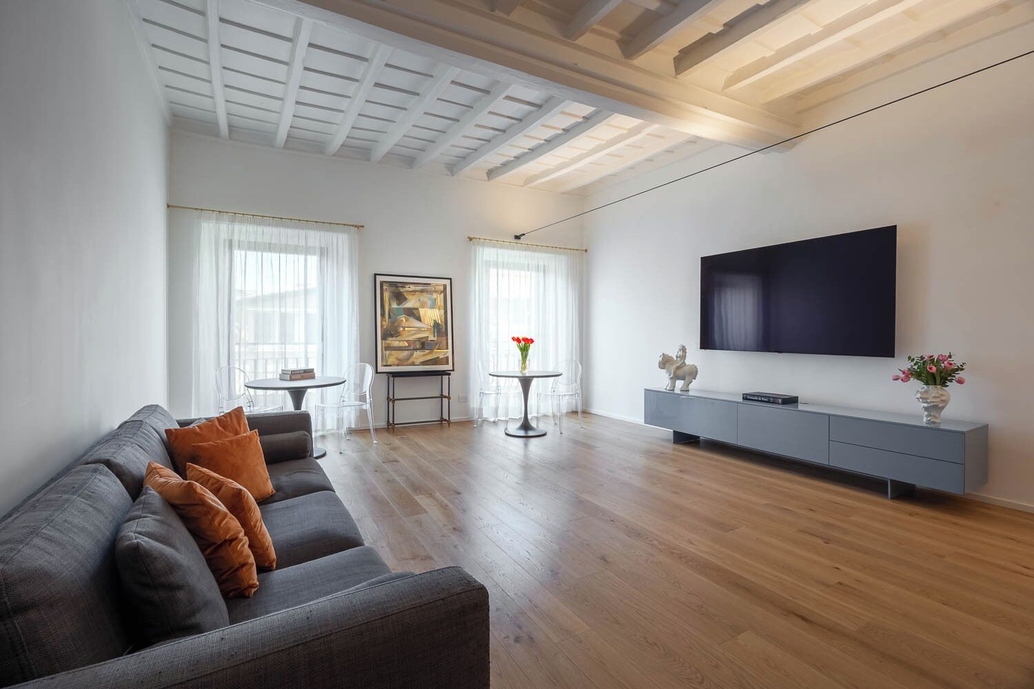 Ein modernes Wohnzimmer mit grauem Sofa, einem Flachbildfernseher und einem minimalistischen Design.