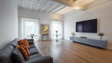 Ein modernes Wohnzimmer mit grauem Sofa, einem Flachbildfernseher und einem minimalistischen Design.