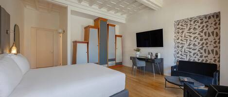 A hotel room with a large bed, a desk with a chair, a flat-screen TV, and a patterned wall.