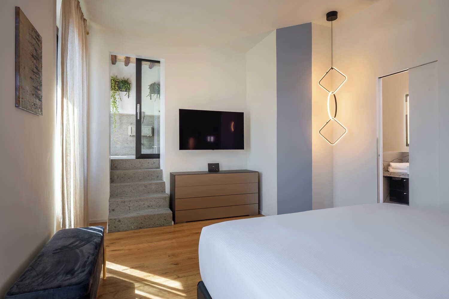 Un dormitorio con cama, cómoda, televisor y una escalera que lleva a un balcón.