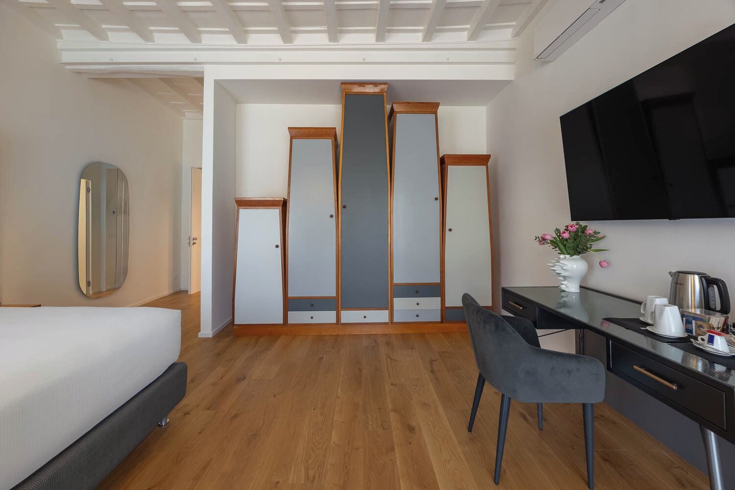 Een hotelkamer met een bed, een bureau, een stoel, een kledingkast, een spiegel en een televisie.