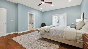 Un dormitorio con cama, ventilador de techo, ventana y puerta.
