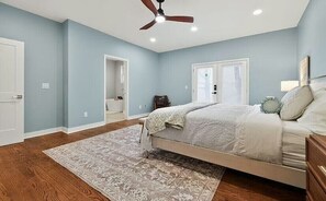 Un dormitorio con cama, ventilador de techo, ventana y puerta.
