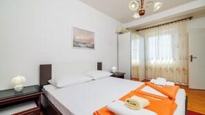 Una habitación de hotel con cama, mesita de noche, lámpara, un cuadro en la pared y ventana con cortinas.