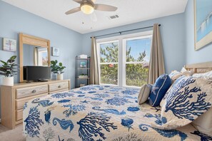A bedroom with a bed, a dresser, a television, a ceiling fan, and a window with curtains. - "Better Together" 4 bed, 2.5 bath , sleeps 10 provides your home away from home. (Ocean Isle Beach)