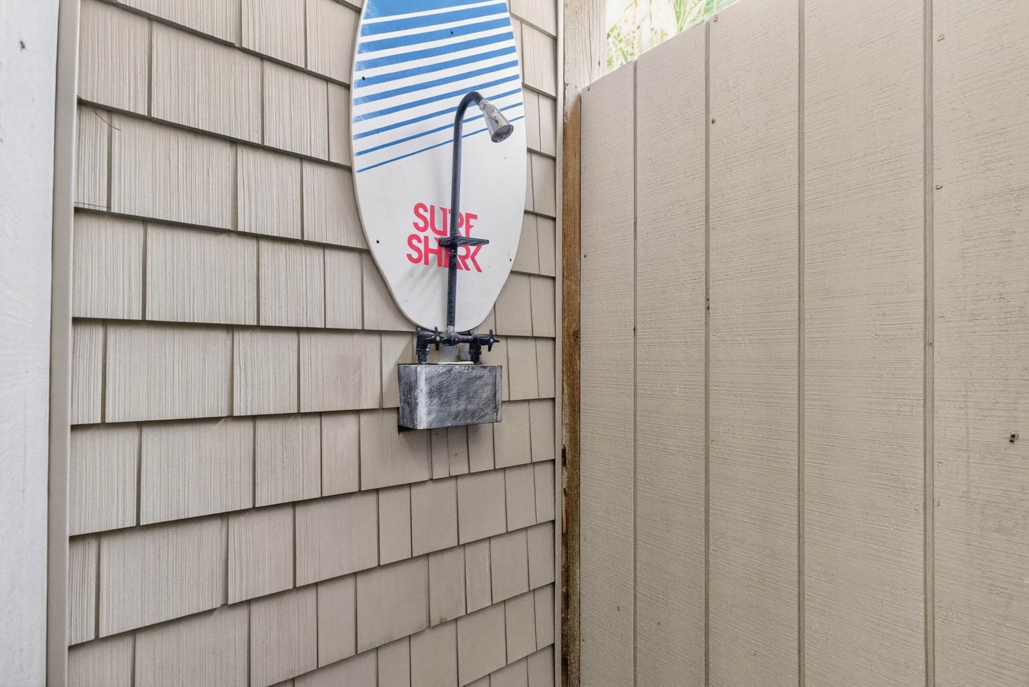 Une pomme de douche en forme de planche de surf, fixée à un mur en bois.