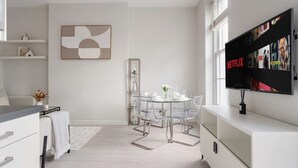Una sala de estar moderna con comedor, televisor de pantalla plana montado en la pared y una decoración minimalista.