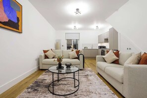 Ein modernes Wohnzimmer mit zwei Sofas, einem Couchtisch und einer Küche im Hintergrund.