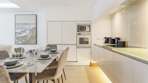 Uma cozinha moderna com forno embutido, micro-ondas e uma área de jantar com mesa posta para quatro pessoas.