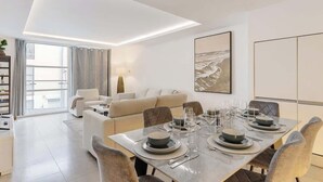 Uma área de refeições moderna com uma mesa posta para quatro pessoas, um sofá e uma janela grande.