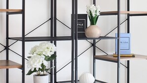 Uma estante de metal com vários níveis e diversos objetos decorativos.