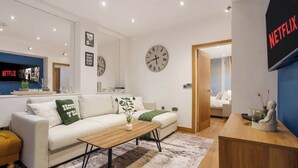 A modern living room with a sofa, coffee table, and a wall clock. - Elegant Fitzrovia Flat in Central London (London)