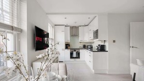 Una cocina moderna con gabinetes blancos, horno empotrado y microondas.