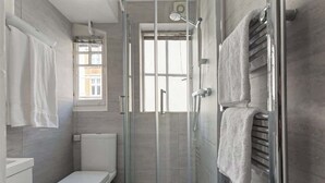 Ein modernes Badezimmer mit einer Duschkabine, einer Toilette und einem Handtuchhalter.