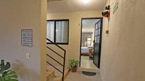 A hallway with a staircase, a potted plant, and a door leading to a bedroom. - Spacious and quiet apartment PKG free of charge (San Miguel de Allende)