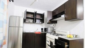 A compact kitchen with a refrigerator, stove, microwave, and dark wooden cabinets. - Spacious and quiet apartment PKG free of charge (San Miguel de Allende)