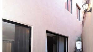 A narrow corridor with a sliding glass door, a small window, and a water dispenser on a counter. - Spacious and quiet apartment PKG free of charge (San Miguel de Allende)