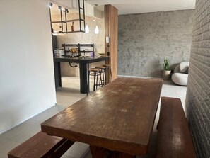Eine moderne Küche mit Holztisch, Barhocker, einer Hängelampe und einer Steinwand.