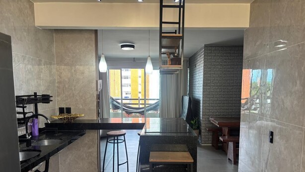 A modern kitchen with a central island, bar stools, and a view of a balcony. - Apartment on Praia do Futuro beach, 200m from the sea. (Fortaleza)
