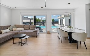 Ein modernes Wohnzimmer mit einer Couch, einem Couchtisch, einem Esstisch und Stühlen.