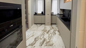 A modern kitchen with marble flooring, built-in appliances, and a central island. - Cerano8 Design Apartment Tortona District (Milano)