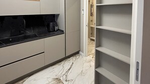 A narrow kitchen with marble flooring, built-in cabinets, and a built-in shelf unit. - Cerano8 Design Apartment Tortona District (Milano)