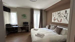 A hotel room with a bed, desk, chair, and artwork on the wall. - Cerano8 Design Apartment Tortona District (Milano)
