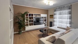 A living room with a sofa, TV, shelves, and a plant. - Cerano8 Design Apartment Tortona District (Milano)