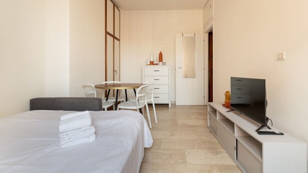 Een hotelkamer met een bed, een bureau, een stoel, een televisie en een kledingkast.