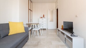 Een gezellig, compact interieur met een bank, een eettafeltje, een televisie en een kitchenette.