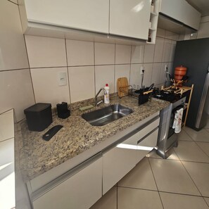 Una cocina con encimera de granito, pileta de acero inoxidable y horno empotrado.