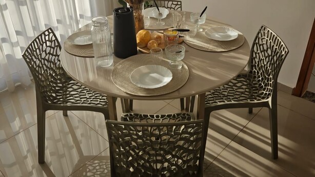 A dining table with four chairs, a vase with dried flowers, a bread basket, and a water bottle. - Comfortable 2-Bedroom AC Apartment  Prime Location for Corporate Travel (São José do Rio Preto)