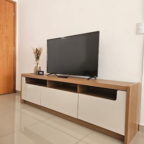Un televisor de pantalla plana sobre un mueble de madera con un gabinete blanco debajo.