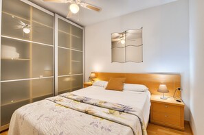 A bedroom with a bed, nightstand, lamp, and a ceiling fan. - Apartment 'Benidorm Poniente' with Communal Pool (Benidorm)