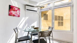 Ein moderner Essbereich mit einem Glastisch, Metallstühlen, einer Schüssel und einer Wand-Klimaanlage.