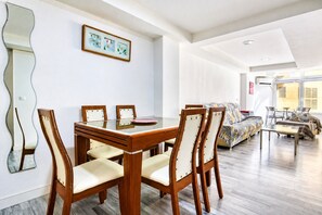 A dining area with a wooden table and chairs, a sofa, and a large mirror on the wall. - Apartment 'Benidorm Poniente' with Communal Pool (Benidorm)