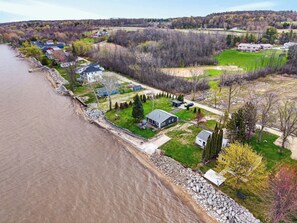A riverfront property with multiple houses, a stone retaining wall, and a grassy area with trees.