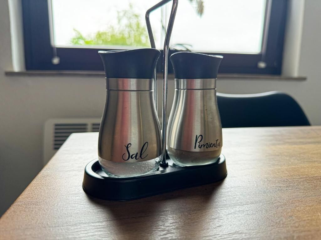 Two stainless steel salt and pepper shakers on a black tray.