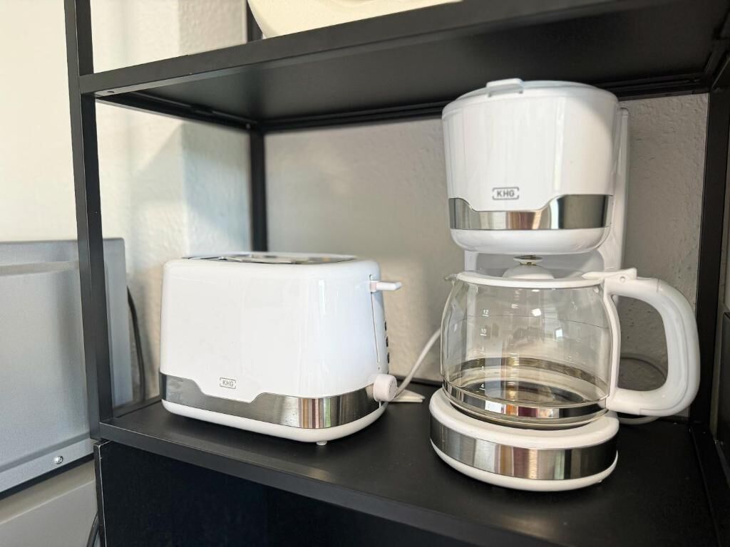 En kaffebryggare och en brödrost står på en svart hylla.