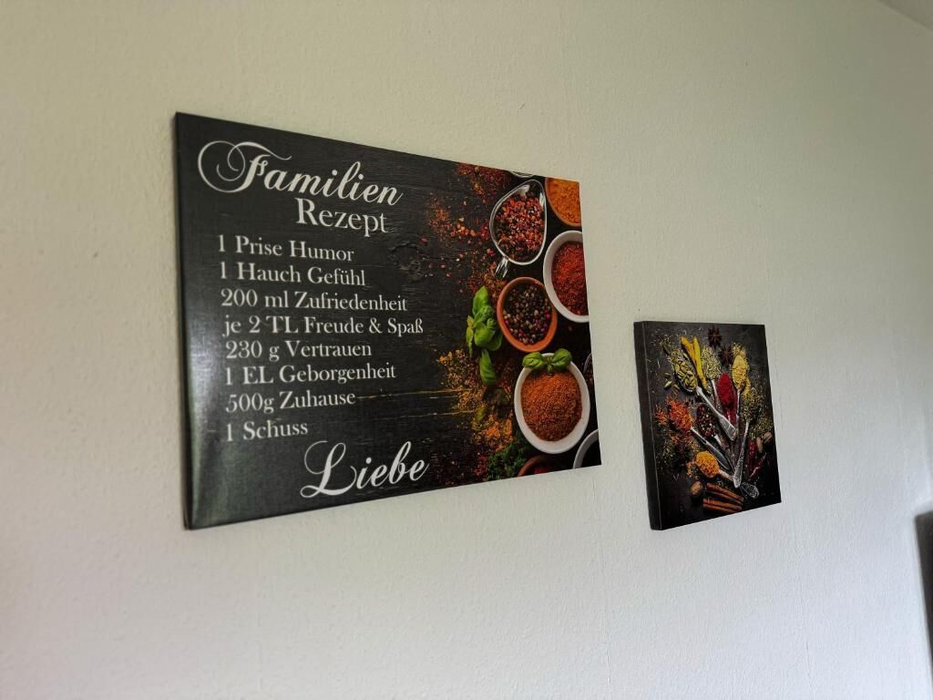 A wall-mounted sign with a family recipe list and a smaller picture of spices.