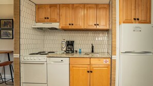 Una cocina con armarios de madera, una estufa blanca y una cafetera.