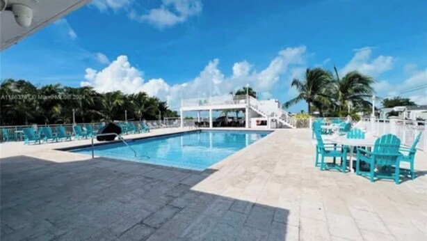 Uma área de piscina com trampolim, espreguiçadeiras e um espaço de estar coberto.