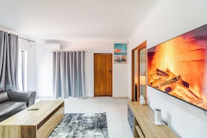 Ein modernes Wohnzimmer mit Sofa, Couchtisch, Fernseher und Vorhängen.