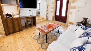 Una sala de estar con piso de madera, un sofá, una mesa de centro, un televisor y una puerta roja.
