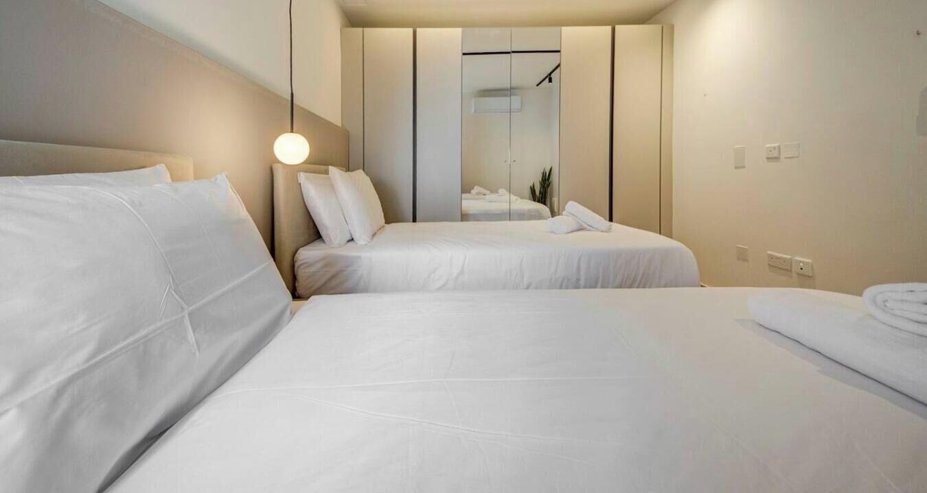 Hotellihuone, jossa on kaksi sänkyä, vaatekaappi ja peili.