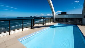 Una piscina en la azotea con vistas despejadas al océano y montañas a la distancia.
