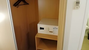 Un armario de madera con una percha y un dispositivo electrónico blanco sobre una estantería.
