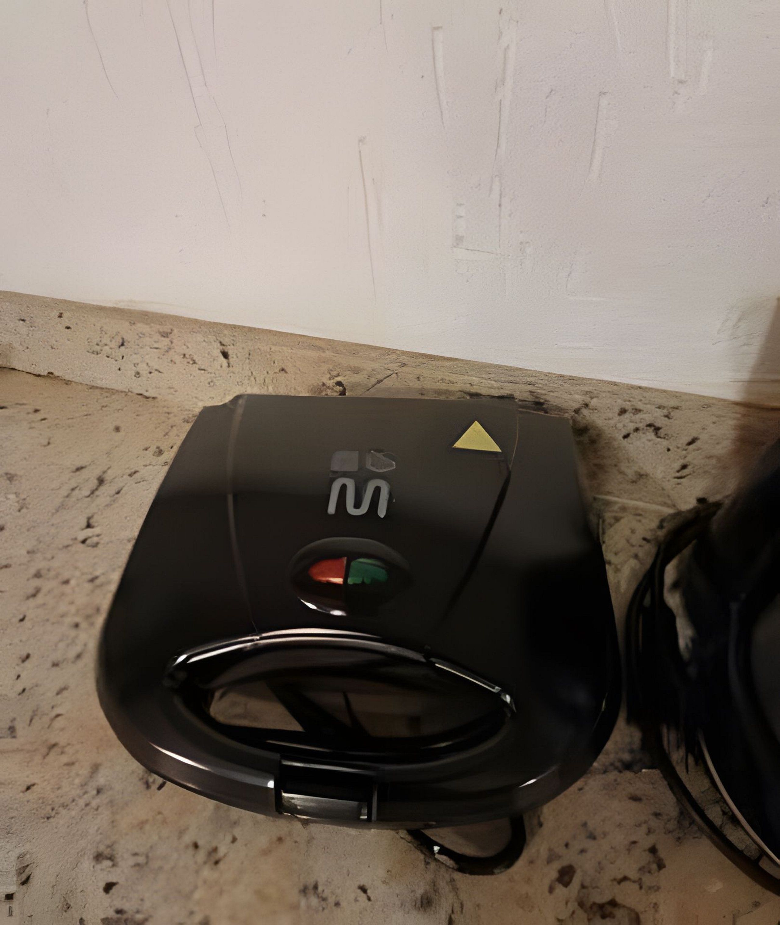 A compact, black, portable device with a control panel featuring a red, green, and yellow button, and a small screen.