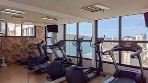 Un gimnasio con cintas de correr, elípticas y un mural colorido en la pared.