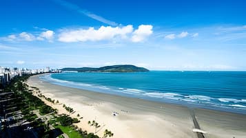 Un paisaje costero con una playa extensa, una pequeña isla y un cielo azul despejado.